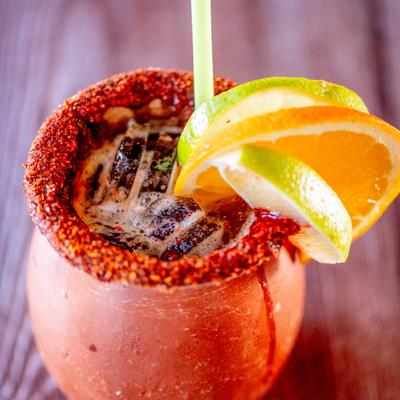 Cantarito drink in a clay mug with tajin chili lime seasoning and citrus slices.