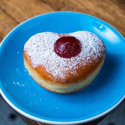 A heart shaped jelly doughnut topped with powdered sugar.