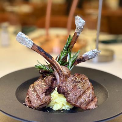 Lamb chops with mashed potatoes and rosemary garnish.