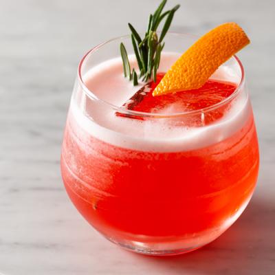 Red cocktail garnished with lemon and rosemary sprig