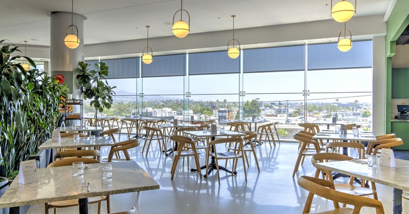 A bright and spacious dining area with large windows and set dining tables