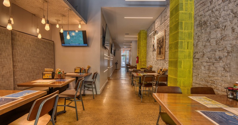 Cozy restaurant interior with pendant lights, wooden tables and exposed brick wall.
