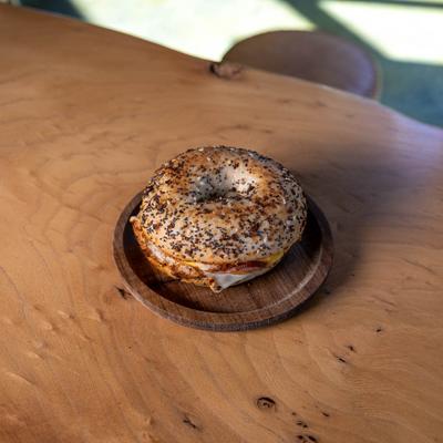 Bacon, egg, and cheese bagel on a wooden plate.
