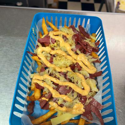 Loaded fries topped with sliced meat, sauerkraut, and creamy sauce.