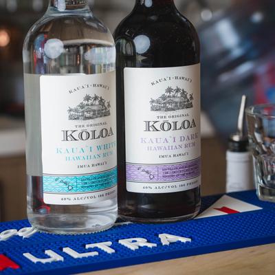 Two tequila bottles on a blue bar mat.