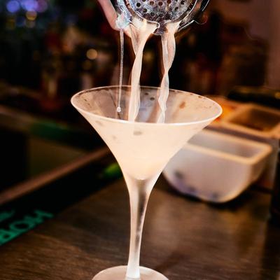 Bartender pouring a Martini from a strainer.