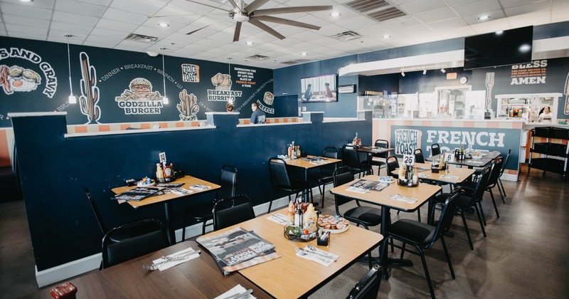Interior of a casual, modern diner-style restaurant with wooden tables and black chairs