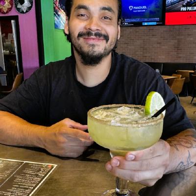 man smiling holding margarita.