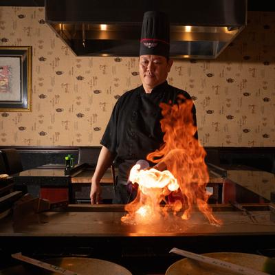 A person preparing food on an open flame.