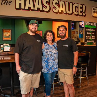 Three friends posing inside a casual bar.