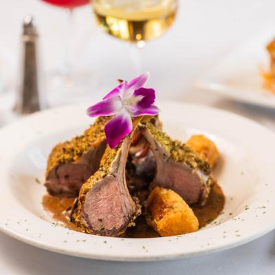 A white plate holds Fresh Herb, Dijon-Crusted Rack of Lamb.