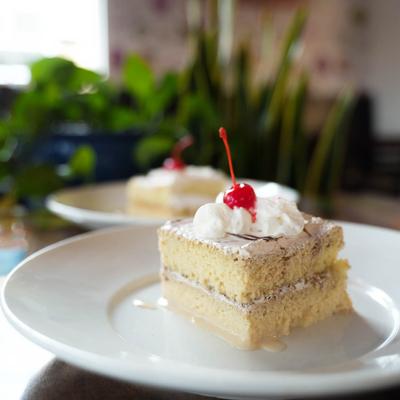 Pastel Tres Leches, topped with whipped cream and a cherry img