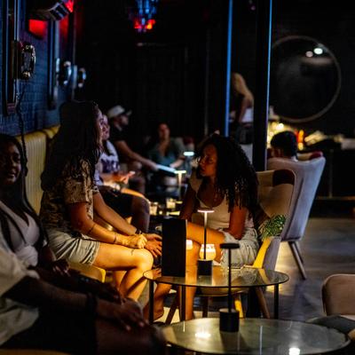 Patrons enjoying drinks and a relaxed ambiance inside a dimly lit lounge.
