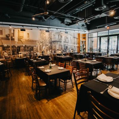 Interior with tables and chairs, black tablecloths, and a large mural on the wall..