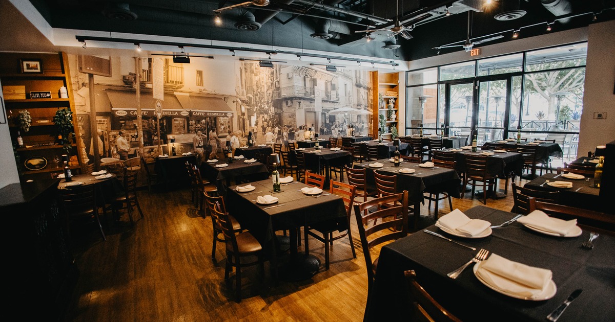 Interior with tables and chairs, black tablecloths, and a large mural on the wall.