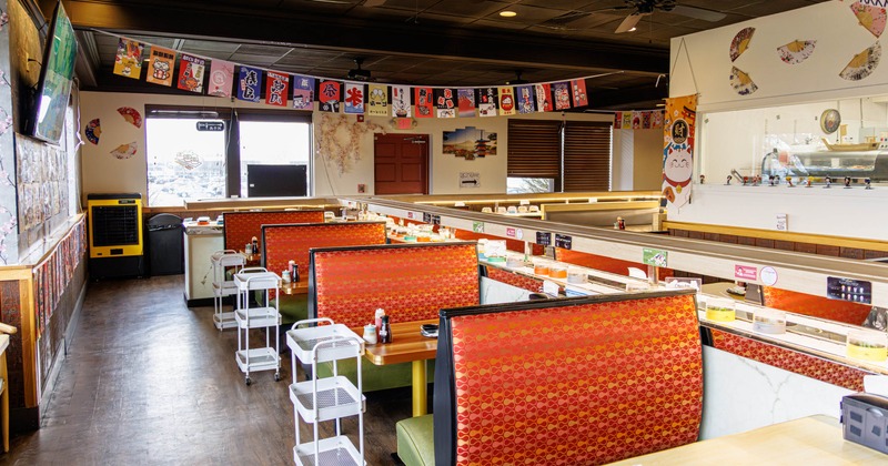 Interior with red booths, sushi conveyor belts, and decor