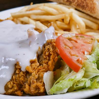 Chicken fried steak with creamy gravy, fries, and salad.