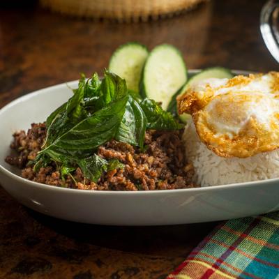 Thai basil minced meat stir-fry served with rice, sliced cucumber, and a fried egg.