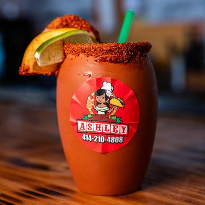 Special cocktail served in a clay cup, with spiced rim, cucumber, lemon, and lime garnish.