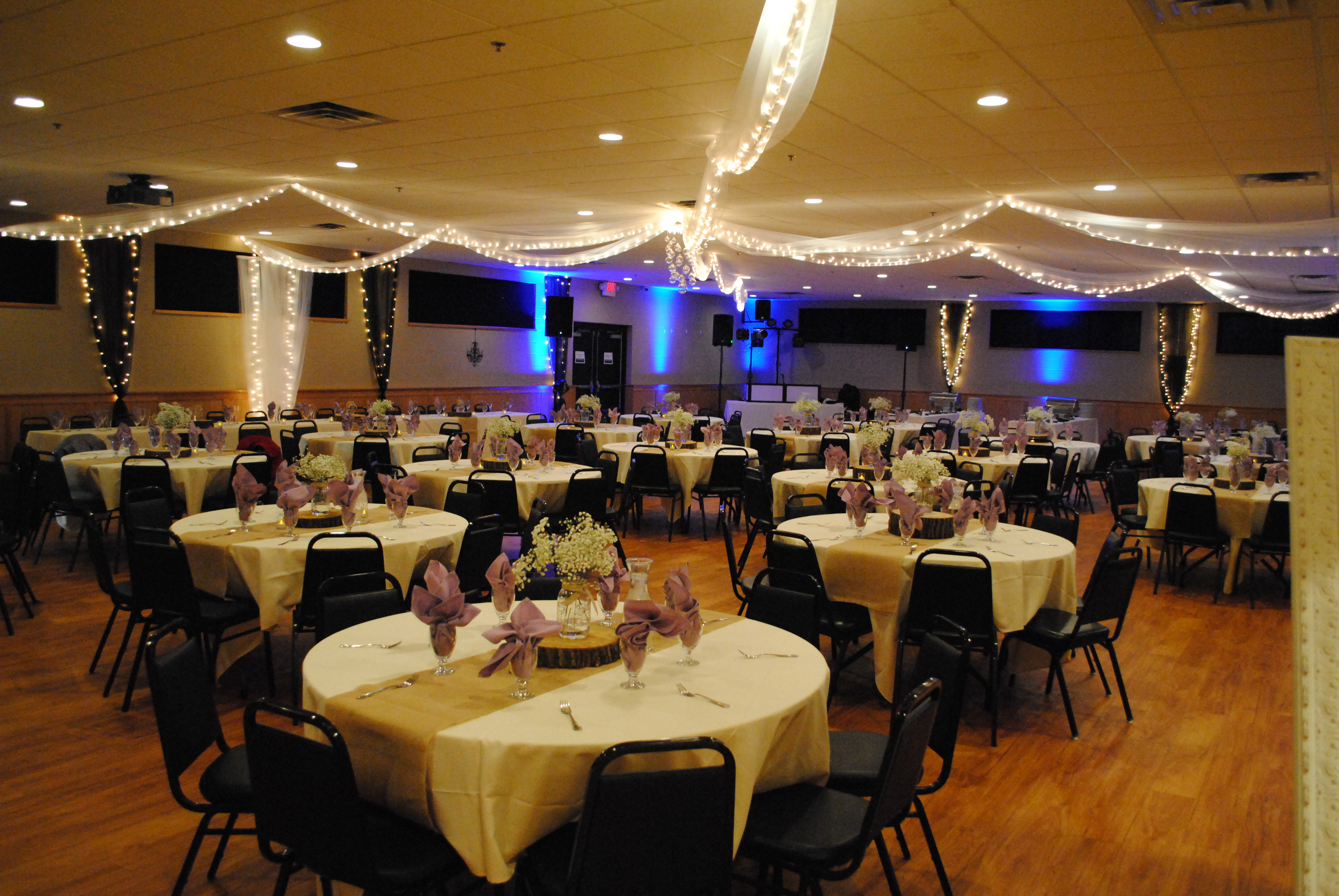 Inrerior with numerous round tables set for an event and ceiling decorations