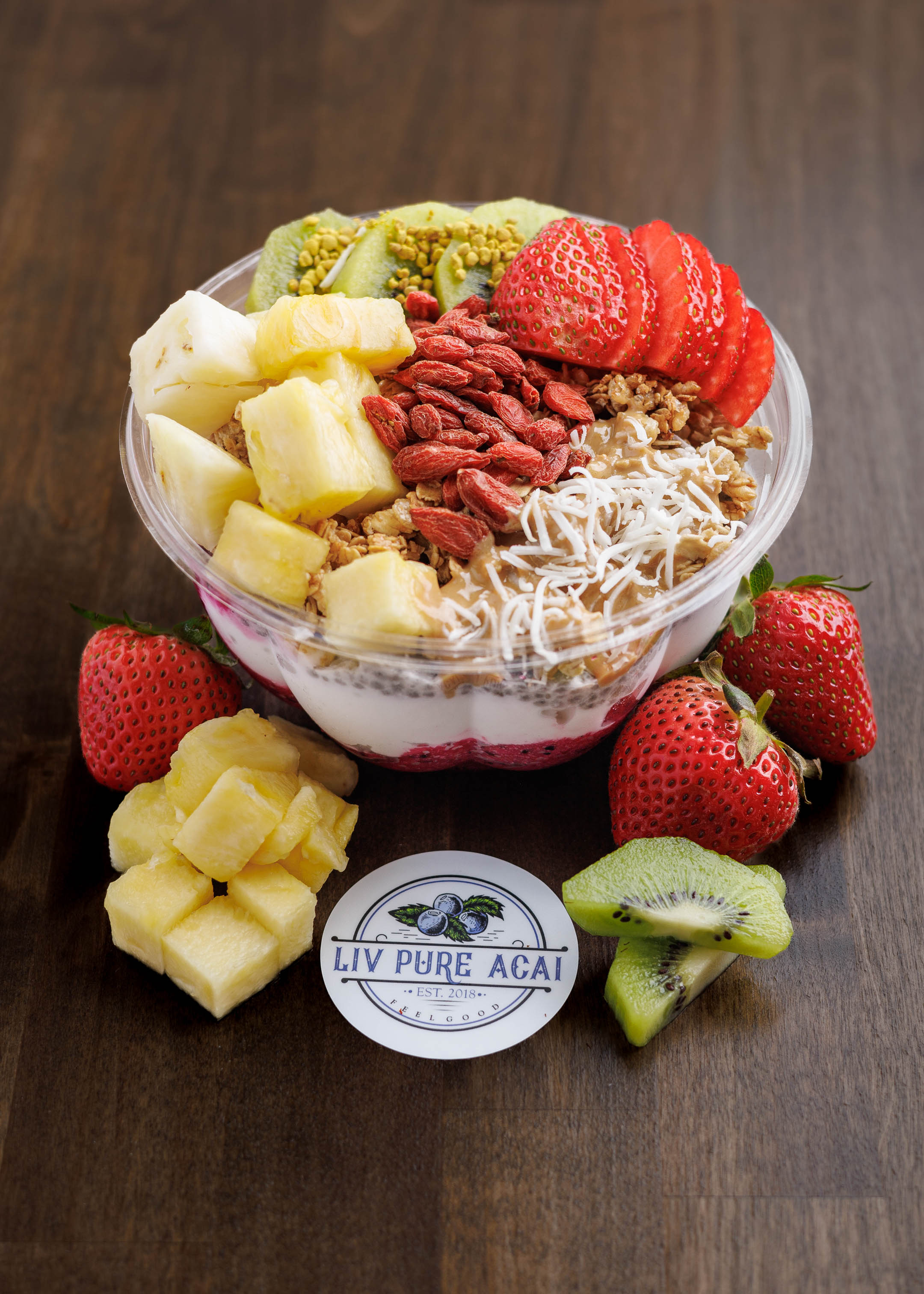 Acai bowl topped with fresh strawberries, pineapple, kiwi, goji berries and coconut flakes