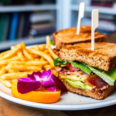 The BLAT sandwich served with fries, garnished with orange slice and a flower.