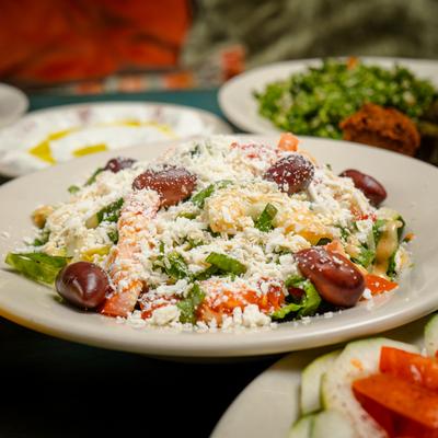 Greek salad plate on a table with other dishes, close up.