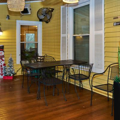 Covered patio with black metal table, chairs, and festive winter decor.