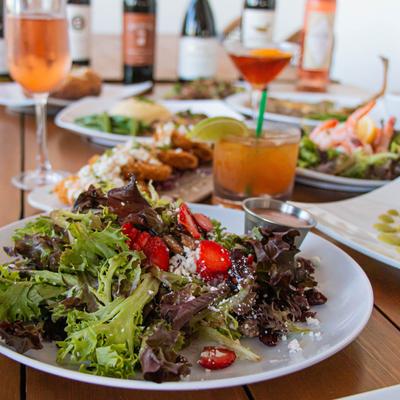Arcadia Strawberry Pecan Salad with Goat Cheese with assorted food plates on a table.