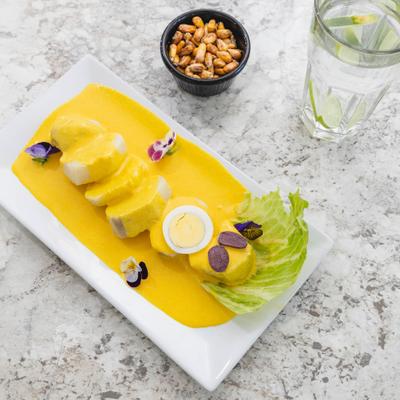 Peruvian boiled potato appetizer with creamy yellow pepper and cheese sauce and toasted corn.