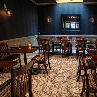 Dim lit dining room featuring wooden tables and chairs on a patterned floor