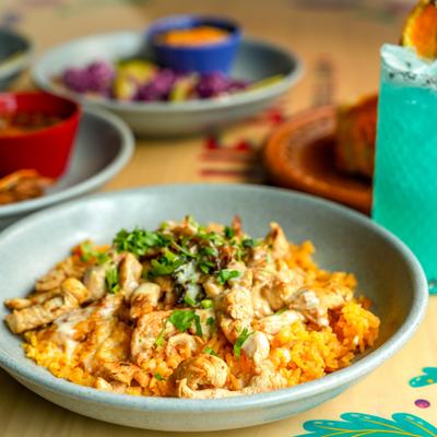 Arroz con Pollo served on the table alongside other dishes and a cocktail.
