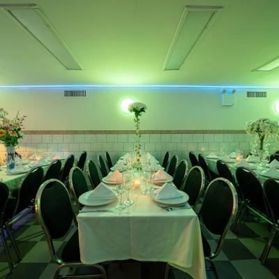 A banquet hall featuring tables set with plates, cutlery, glassware and floral centerpieces.