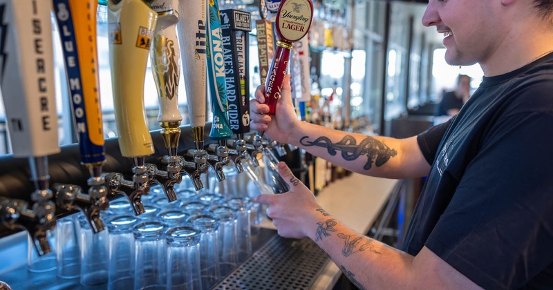 A bartender pouring tap beer into a glass