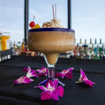 Bushwacker cocktail garnished with whipped cream. pineapple and a cherry.