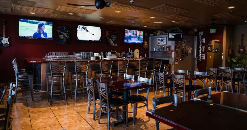 Cozy interior seating area and bar with upholstered stools and TVs above