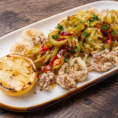 Fried calamari served with peppers, herbs, and a charred lemon half.