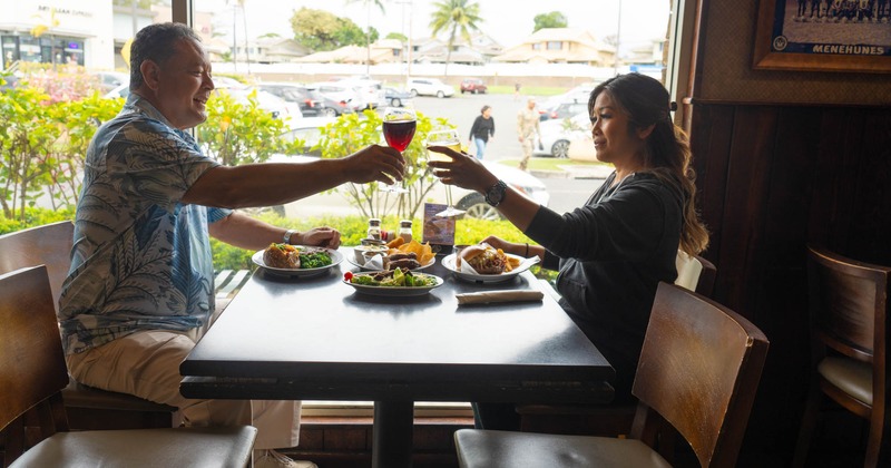 Guests are toasting with wine at the diner table by the window