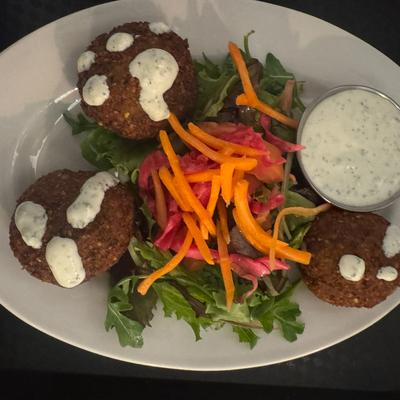 Falafel over greens with pickled vegetables and herb sauce.