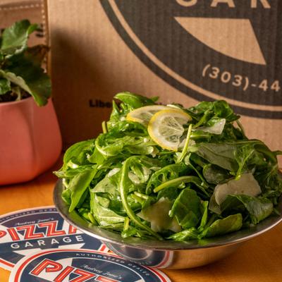 Arugula salad served in a metallic bowl.