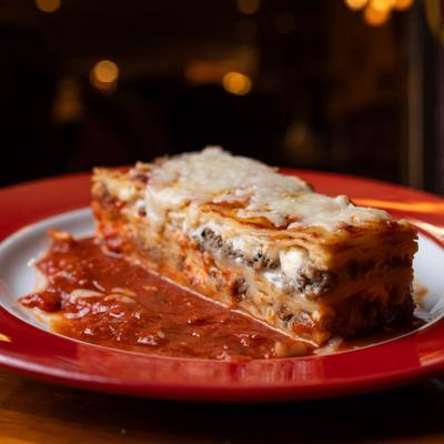 Baked lasagna slice with tomato sauce.