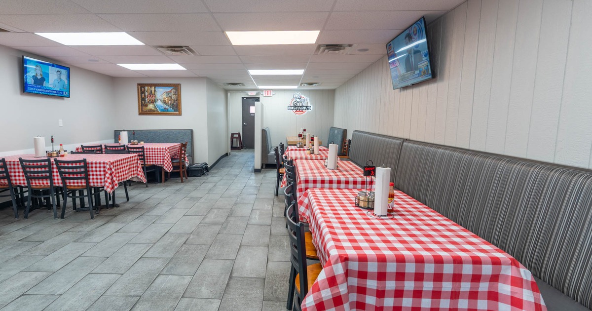 Interior of a restaurant with tables covered in red and white checkered tablecloths