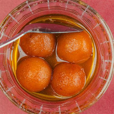 Gulab Jamun served in a glass bowl, top down view.