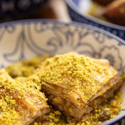 Baklava topped with a generous amount of finely ground pistachios.