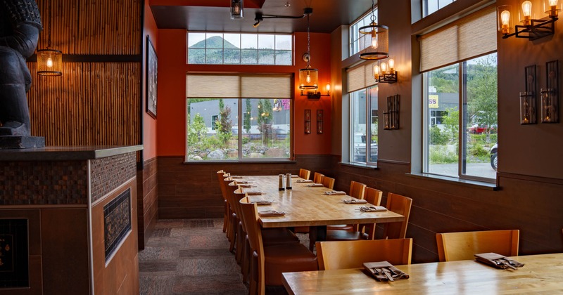 Interior of a restaurant featuring a long wooden table, wooden paneling, warm orange walls