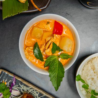 Bowl of Pineapple Curry garnished with Thai basil, top view.