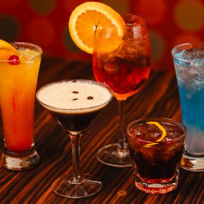 Assorted colorful cocktails on a wooden table.