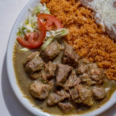 Pork stew served with beans, rice, and salad.
