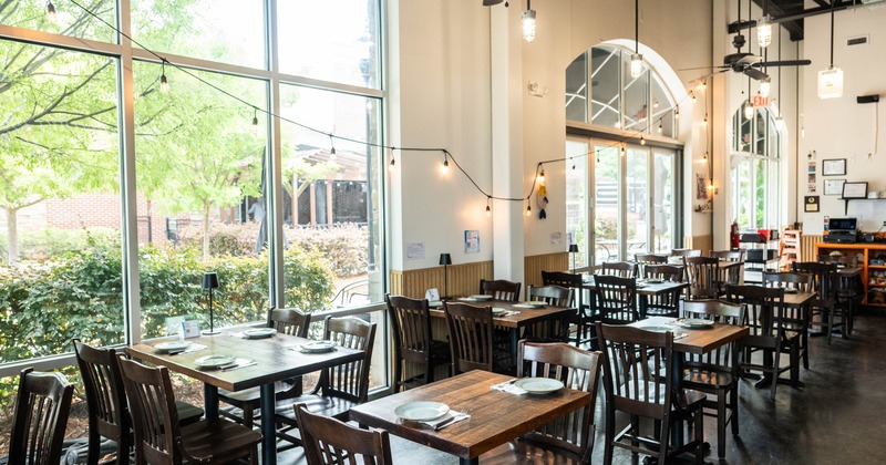 Bright, airy restaurant with wooden tables and chairs set for dining
