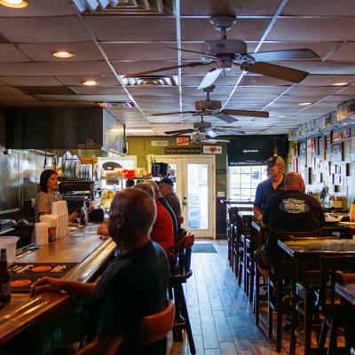 Interior with both counter and table seating, ceiling fans and wall decorations.